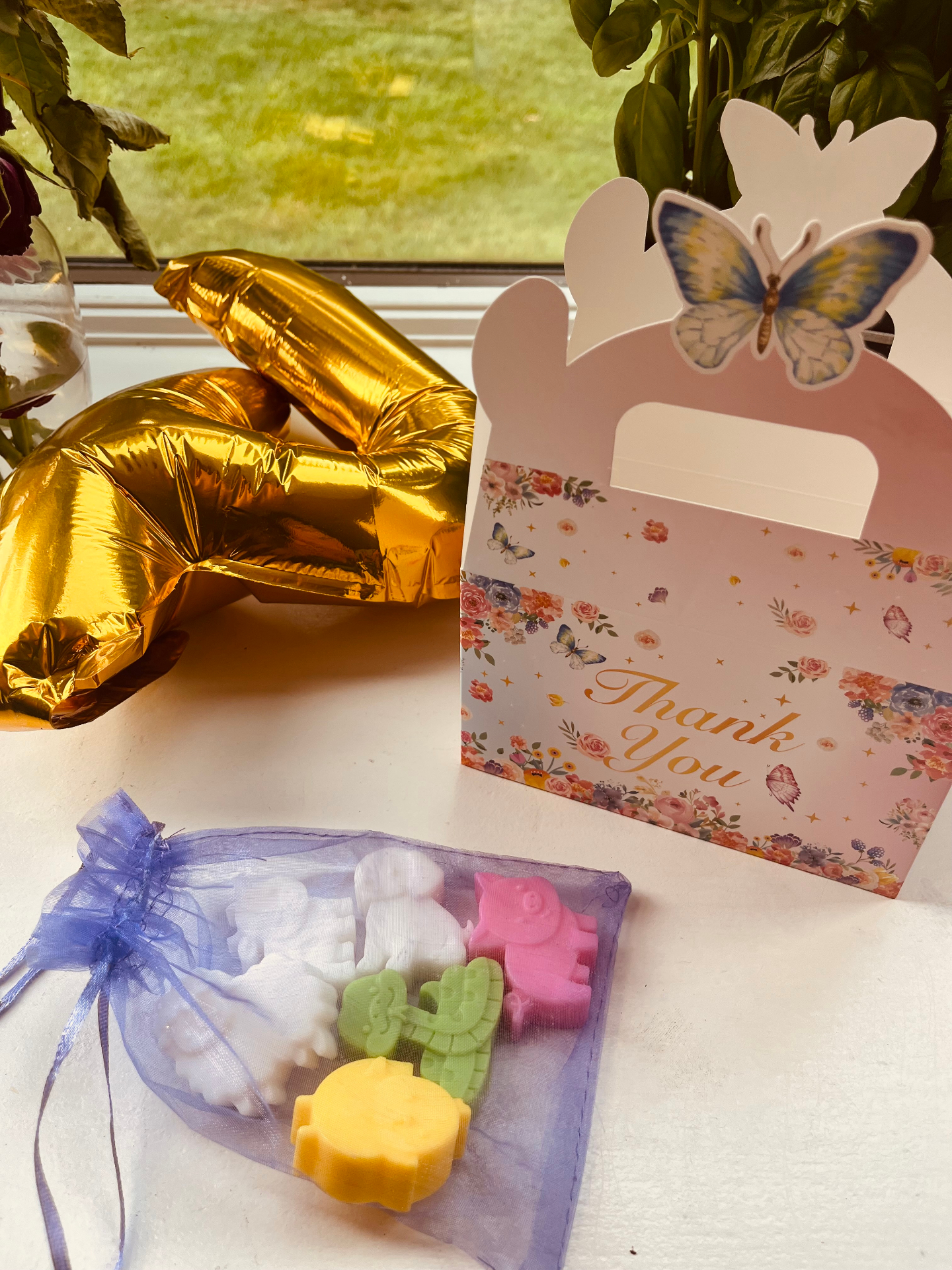 Colorful animal-shaped soaps in a lavender organza bag next to a butterfly thank-you gift box